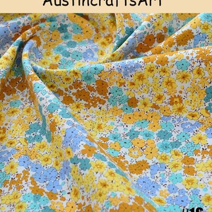 K&ouml;nnte beinhalten: Stoff mit einem dichten Blumenmuster aus kleinen gelben, goldorangen und hellblauen Bl&uuml;ten auf wei&szlig;em Grund. Der Text Austin crafts Art erscheint oben und die Zahl 16 ist in der unteren rechten Ecke des Bildes aufgedruckt.