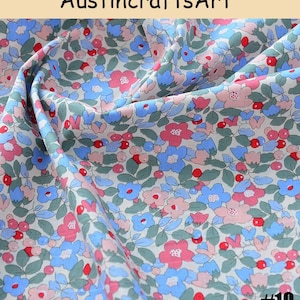K&ouml;nnte beinhalten: Stoff mit einem dichten Blumenmuster aus hellblauen, rosafarbenen und roten Bl&uuml;ten, durchsetzt mit gr&uuml;nen Bl&auml;ttern auf wei&szlig;em Grund. Der Text AustincraftsArt und #10 sind sichtbar. Der Stoff ist drapiert, um Textur und Falten zu zeigen.