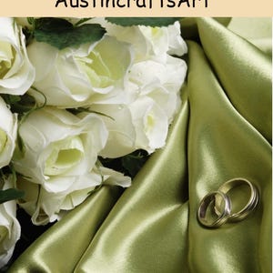May include: A bouquet of white roses with green leaves resting on a draped olive green satin fabric next to two metallic rings. The text AustincraftsArt is visible at the top of the image. The composition features soft lighting and floral textures.