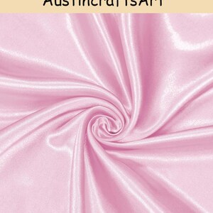 May include: A piece of light pink satin fabric with a smooth, glossy finish and a swirling, draped texture. The text "AustincraftsArt" is printed in black at the top of the image against a light beige background.