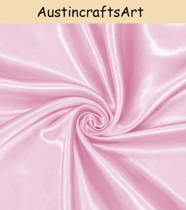 May include: A piece of light pink satin fabric with a smooth, glossy finish and a swirling, draped texture. The text "AustincraftsArt" is printed in black at the top of the image against a light beige background.