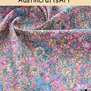 K&ouml;nnte beinhalten: Ein rosa Stoff mit einem dichten Blumenmuster aus gelben, blauen und wei&szlig;en Bl&uuml;ten sowie gr&uuml;nen Bl&auml;ttern. Der Text Austin crafts Art steht oben und die Zahl 4 befindet sich in der unteren rechten Ecke dieses Textilmaterials.