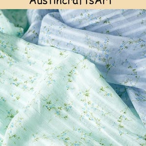 May include: A lightweight fabric featuring a delicate floral pattern with tiny blue flowers and green vines on a striped background. The material is shown in two color variations, a soft mint green and a pale sky blue, with the text AustincraftsArt.