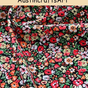 K&ouml;nnte beinhalten: Stoff mit einem dichten Blumenmuster aus roten, orangen, gelben und wei&szlig;en Bl&uuml;ten auf schwarzem Grund. Das Textil weist Falten und Drapierungen auf und zeigt einen sich wiederholenden botanischen Druck. Der Text Austin crafts Art und #8 ist sichtbar.