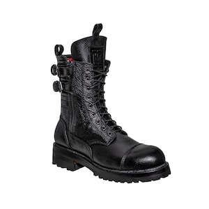 May include: Black leather combat boot with a textured finish. The boot features a lace-up design, two buckle straps, and a pull tab at the top. The sole is thick and lugged.