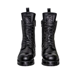 May include: A pair of black leather combat boots with a textured finish. The boots have a lace-up design, side zippers, and a logo embossed on the tongue. The soles are thick and lugged.