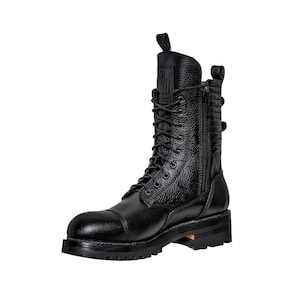 May include: Black leather combat boot with a cap toe, lace-up closure, and side zipper. The boot features a textured leather upper, a pull tab at the top, and a chunky sole. The boot has a rugged, industrial aesthetic.