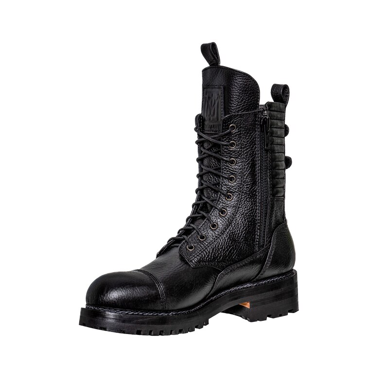 May include: Black leather combat boot with a cap toe, lace-up closure, and side zipper. The boot features a textured leather upper, a pull tab at the top, and a chunky sole. The boot has a rugged, industrial aesthetic.