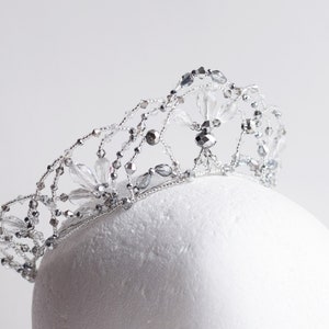 May include: A silver tiara with clear crystal beads and a delicate floral design.