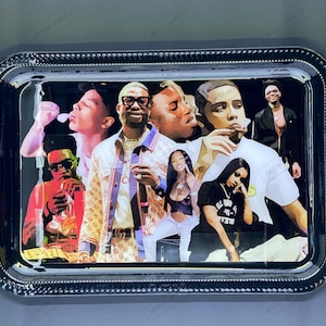 Puede incluir: Bandeja de rodadura de metal negro con un estampado gráfico colorido de varias personas. El estampado presenta un grupo de personas con varios peinados y ropa, incluyendo una persona que lleva una camisa estampada y una persona que lleva una camisa negra con el texto "BLVD 15-16" impreso en ella.