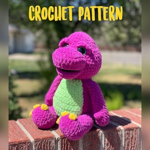 May include: Crochet pattern for a purple and green dinosaur plush toy. The toy is sitting on a brick wall. The text "CROCHET PATTERN" is written in yellow letters at the top of the image.
