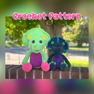 May include: Two crocheted dinosaur plush toys. One is green with a purple belly and pink feet, the other is dark blue with a purple belly and green feet. The text "Crochet Pattern" is displayed in pink above the toys.