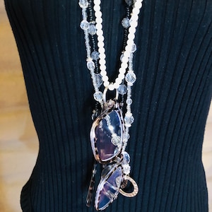 May include: A layered necklace with white and clear beads, and a pair of glasses attached to the bottom.