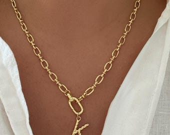 May include: Gold-coloured chain necklace with a pendant featuring the letter "K". The necklace has a textured, braided design on the letter and a clasp closure. The chain is made of oval links.