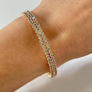 May include: A gold bracelet with a double row of clear round stones.