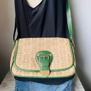 Bolso de mano de lona beige y cuero verde con logotipo de Etienne Aigner, herrajes plateados, cierre de cremallera, correa de 24 pulgadas, en excelente estado.
