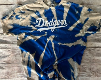 Może przedstawiać: Koszulka tie-dye w kolorze niebieskim i białym z napisem "Dodgers" w białych literach.