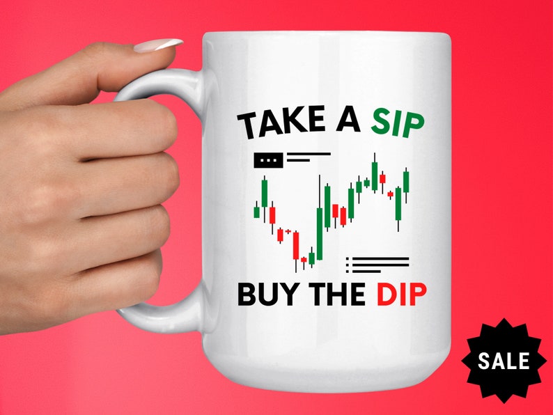 May include: White ceramic mug with a black and green graphic of a stock market chart and the text "TAKE A SIP BUY THE DIP".