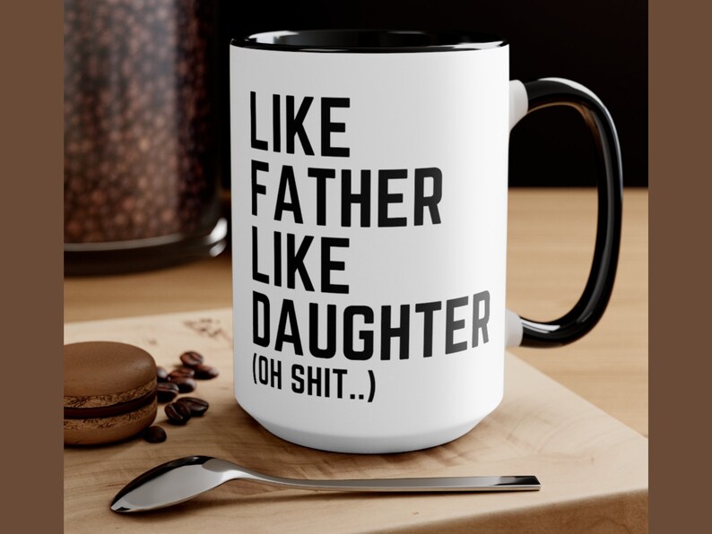 May include: White ceramic coffee mug with a black rim and handle. The mug has black text that reads "Like Father Like Daughter (Oh Shit..)"