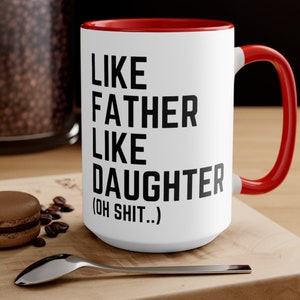 May include: White ceramic coffee mug with a red rim and handle. The mug has black text that reads "Like Father Like Daughter (Oh Shit..)"