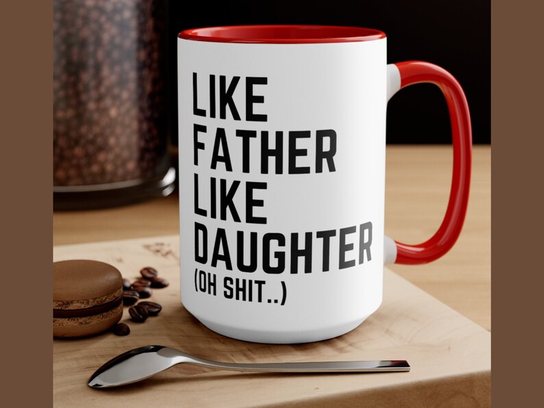 May include: White ceramic coffee mug with a red rim and handle. The mug has black text that reads "Like Father Like Daughter (Oh Shit..)"