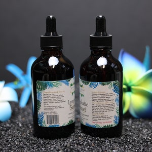 May include: Two dark brown glass bottles with droppers, labelled "Lymphatic Support". The bottles are on a black surface with blue and green flowers.