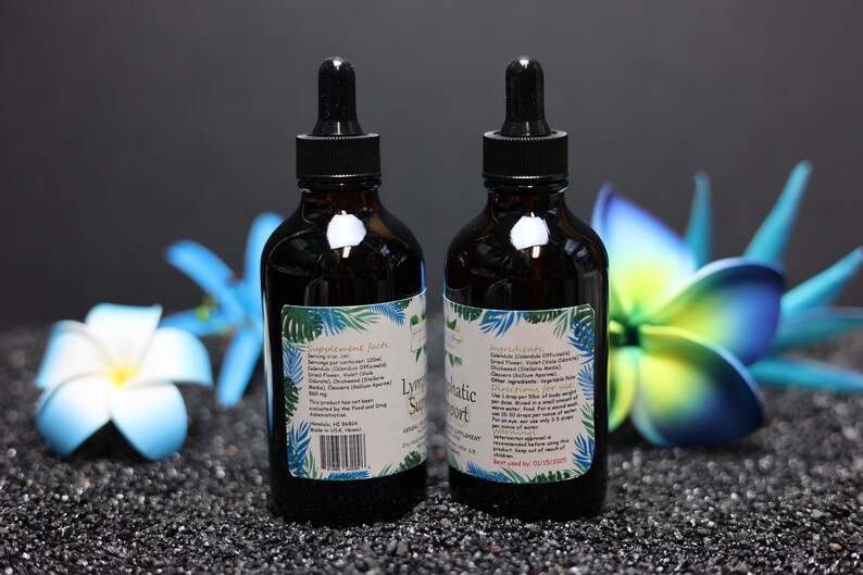 May include: Two dark brown glass bottles with droppers, labelled "Lymphatic Support". The bottles are on a black surface with blue and green flowers.