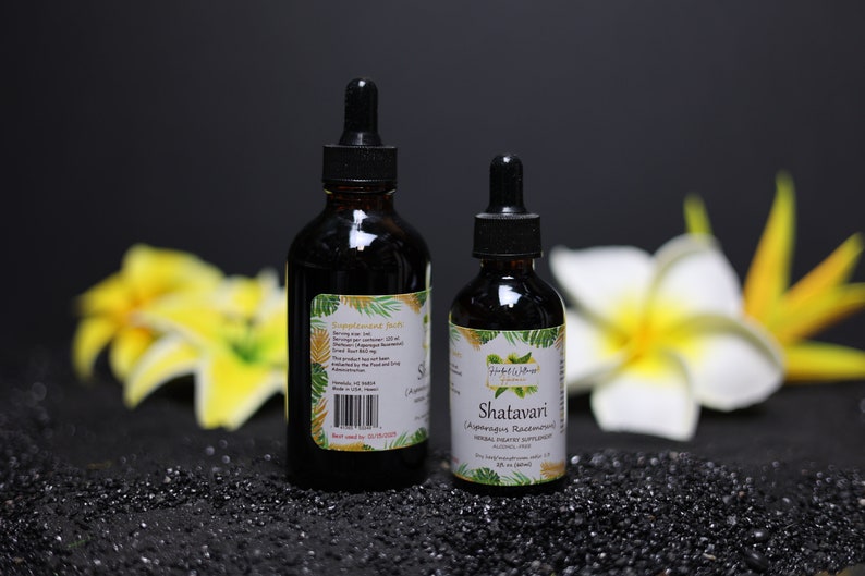 May include: Two brown glass bottles with dropper tops, one larger than the other, on a black surface. The smaller bottle has a label that reads "Shatavari" and "Ayurvedic Rejuvenating Herbal Dietary Supplement". The larger bottle has a label with text that is too small to read.