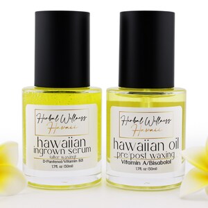 May include: Two clear glass bottles with black caps and yellow liquid inside. The bottles are labelled "Hawaiian Ingrown Serum" and "Hawaiian Oil Pre/Post Waxing". The bottles are sitting on a white surface with two yellow plumeria flowers.