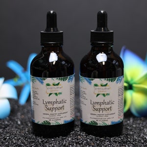 May include: Two brown glass bottles with droppers, labelled "Lymphatic Support" and "Herbal Dietary Supplement, Alcohol Free". The bottles are on a black surface with blue and white flowers.
