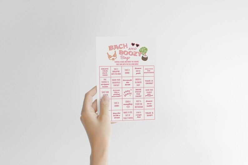 May include: A white card with pink text that reads "Bach and Boozy Bingo." The card features illustrations of a bikini top, a cocktail, and a tropical plant. The bingo card has various prompts for a bachelorette party.