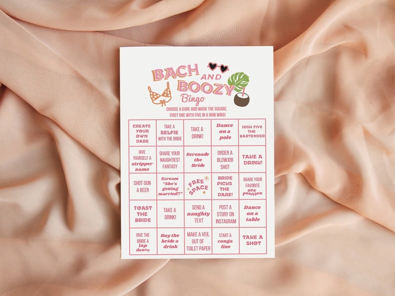 May include: A rectangular card with the text "BACH AND BOOZY Bingo" in pink and orange. The bingo card features various dares, including "Take a selfie with the bride" and "Dance on a pole." The card has a tropical theme with bikini and palm tree illustrations.