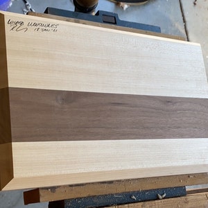 May include: A rectangular wooden cutting board with a light wood top and a dark wood center strip. The board is signed "Lloyd Woodworks 17 Jan '21".