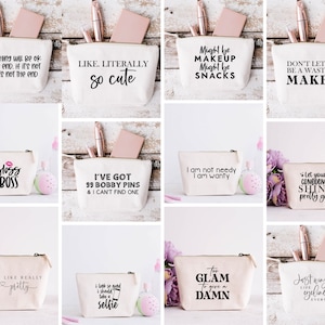 May include: A collection of canvas cosmetic bags with various black text designs. Some bags include phrases like "Like. Literally so cute," "Gloss Boss," and "Too Glam to give a Damn." Each bag has a zipper closure and contains makeup items.