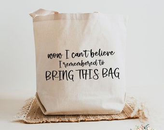 Op de afbeelding: Een witte canvas tote bag met zwarte tekst die "wow I can't believe I remembered to BRING THIS BAG" zegt.