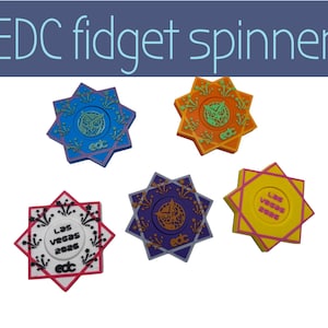 Puede incluir: Cinco fidget spinners en forma de estrella en azul, naranja, morado, rojo y amarillo. Cada spinner tiene diseños únicos y el texto "EDC fidget spinners" en la parte superior. Diseñados para aliviar el estrés.
