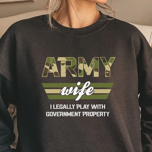 May include: Black sweatshirt with a camouflage print and the text "ARMY wife I LEGALLY PLAY WITH GOVERNMENT PROPERTY".