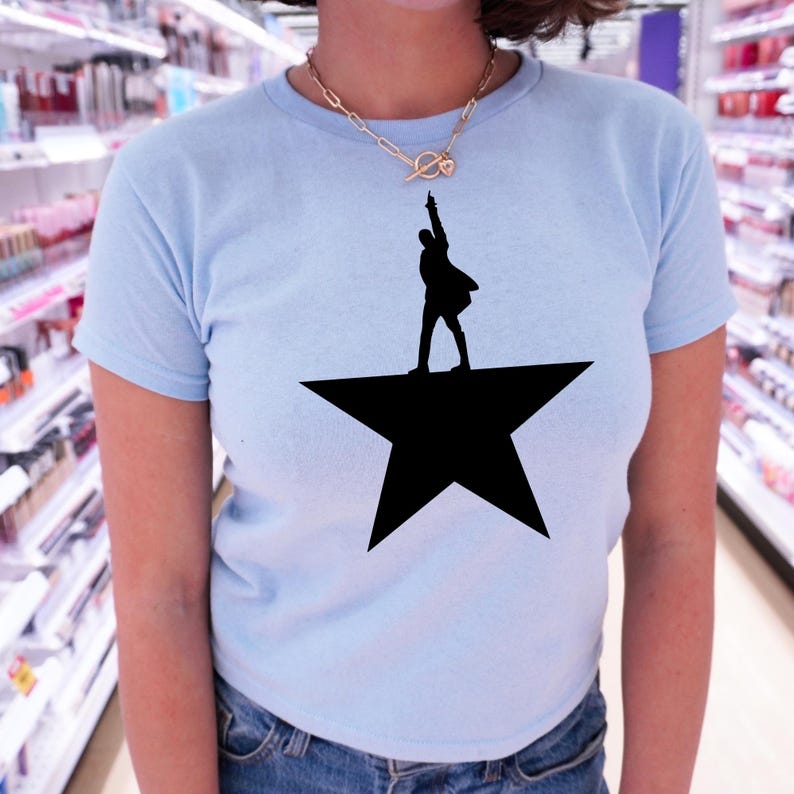 A person wearing a light blue t-shirt with a black silhouette of a person standing on a star.