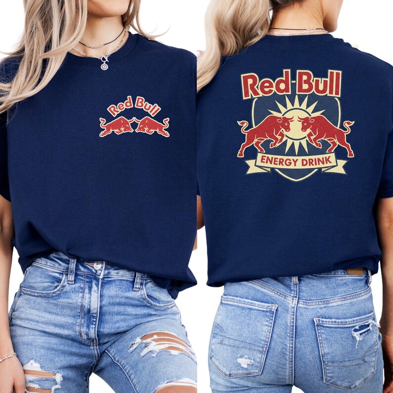 a woman wearing a navy blue t-shirt with the Red Bull logo and a shield-shaped emblem featuring two red bulls. She is also wearing distressed jeans.
