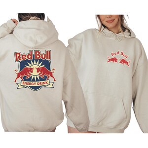 two people wearing white hooded sweatshirts with the Red Bull logo.