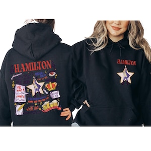 A black hoodie with colorful text and graphics on the back, and a woman wearing the hoodie smiling.