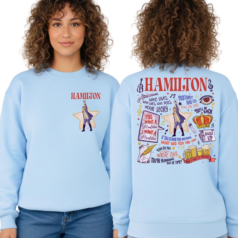 A woman wearing a light blue sweatshirt with a colorful graphic design on the back.