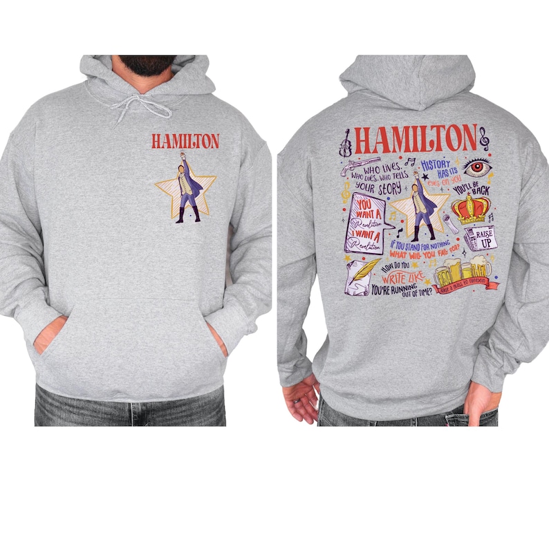 A gray hoodie with a colorful graphic design featuring various text elements and illustrations related to the character Hamilton from the musical Hamilton.