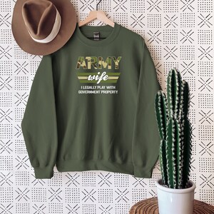 May include: Green army wife sweatshirt with camouflage print and the text "ARMY wife I LEGALLY PLAY WITH GOVERNMENT PROPERTY".