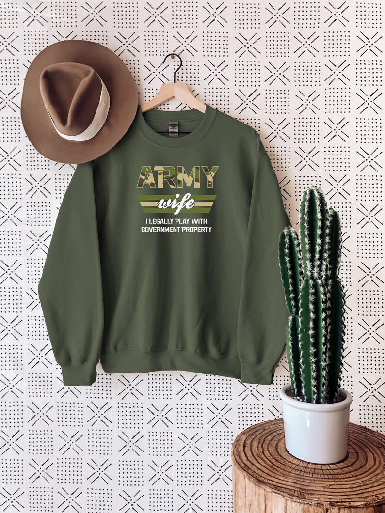 May include: Green army wife sweatshirt with camouflage print and the text "ARMY wife I LEGALLY PLAY WITH GOVERNMENT PROPERTY".