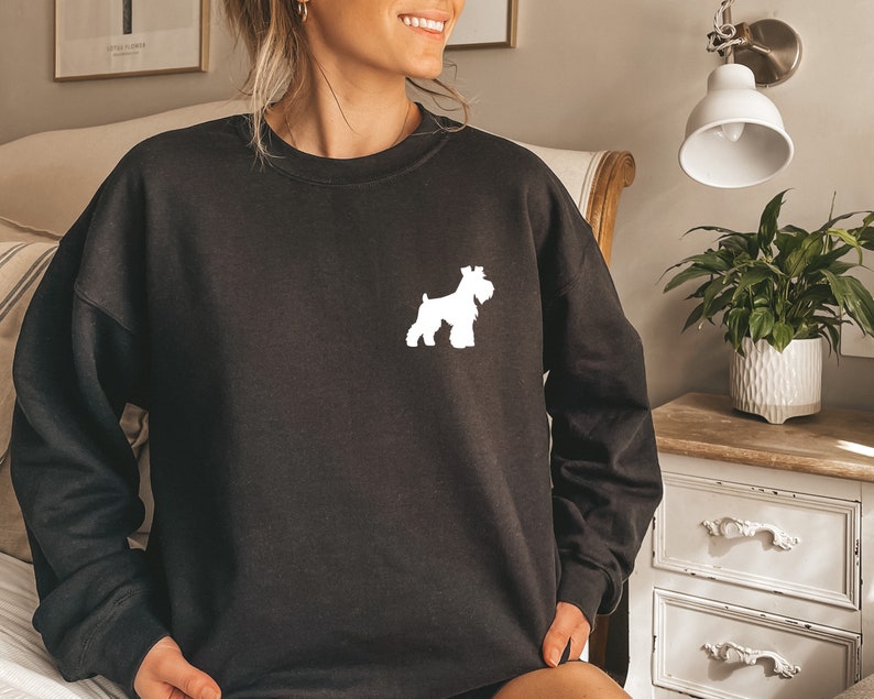 May include: Black sweatshirt with a white silhouette of a Schnauzer dog on the front.