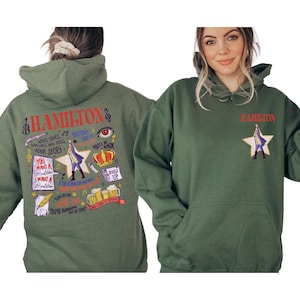 A woman wearing a green hoodie with various text and graphics printed on it, including a character from the musical Hamilton.