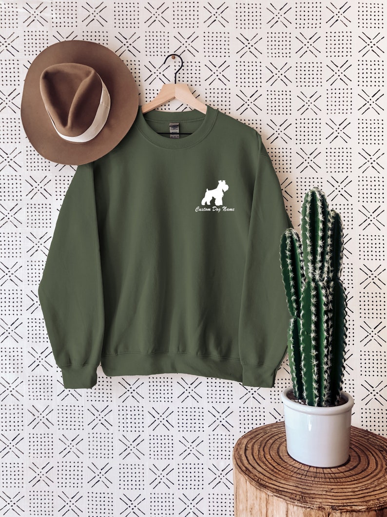 May include: A green sweatshirt with a white silhouette of a Schnauzer dog and the text "Custom Dog Name".