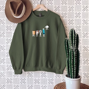 May include: A green sweatshirt with a graphic of a series of figures carrying different forms of data storage, including floppy disks, a CD, a USB drive, and a cloud. The figures are walking towards a cloud.