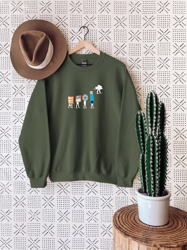 May include: A green sweatshirt with a graphic of a series of figures carrying different forms of data storage, including floppy disks, a CD, a USB drive, and a cloud. The figures are walking towards a cloud.